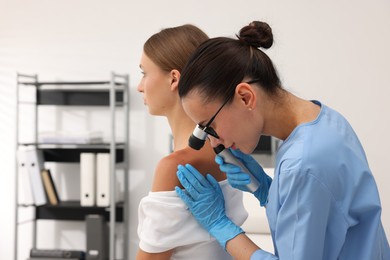 Photo of Doctor examining young woman's mole with dermatoscope in hospital