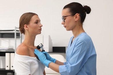 Photo of Doctor examining young woman's mole with dermatoscope in hospital