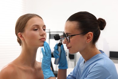 Photo of Doctor examining young woman's mole with dermatoscope in hospital