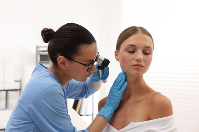 Photo of Doctor examining young woman's mole with dermatoscope in hospital