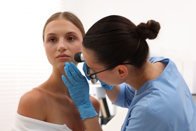 Photo of Doctor examining young woman's mole with dermatoscope in hospital