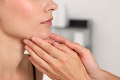 Photo of Doctor examining young woman's mole in hospital, closeup