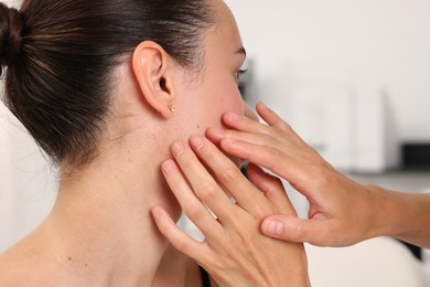 Photo of Doctor examining young woman's mole in hospital, closeup