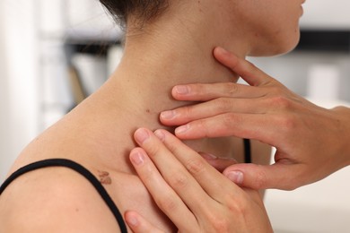 Photo of Doctor examining young woman's mole in hospital, closeup