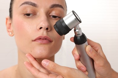 Photo of Doctor examining young woman's mole with dermatoscope in hospital, closeup
