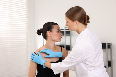 Photo of Doctor examining young woman's mole in hospital