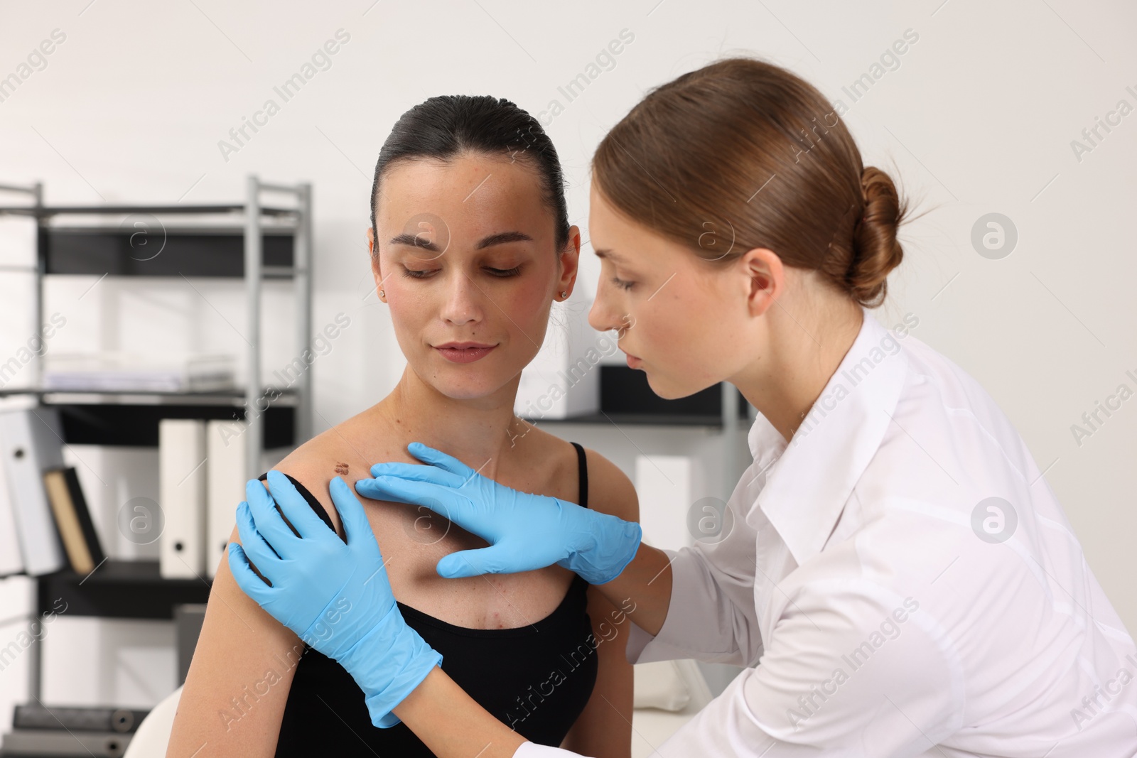 Doctor examining young woman's mole in hospital Photo of Doctor examining young woman's mole in hospital