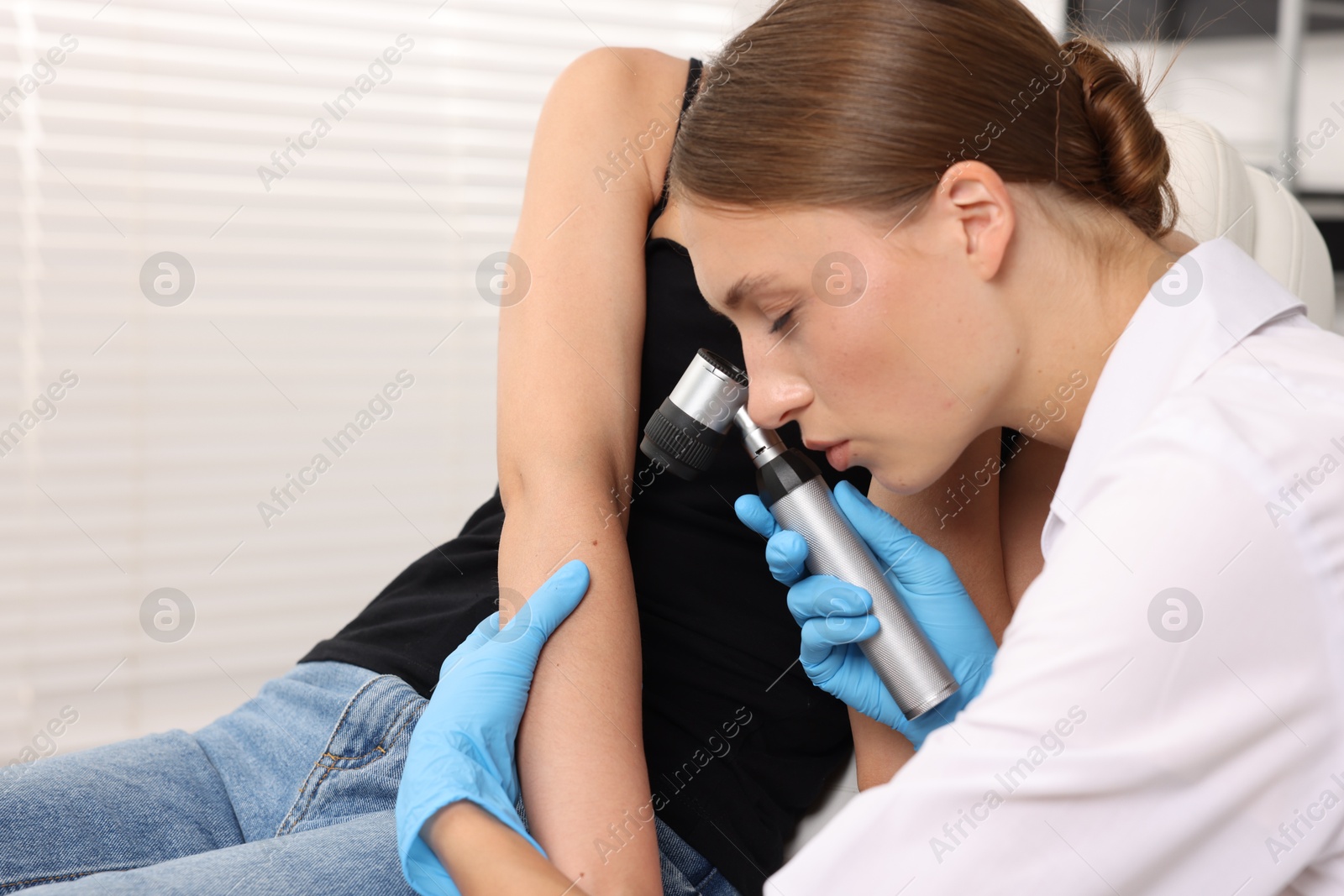 Photo of Doctor examining young woman's mole with dermatoscope in hospital