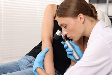 Photo of Doctor examining young woman's mole with dermatoscope in hospital