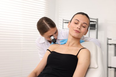 Photo of Doctor examining young woman's mole with dermatoscope in hospital