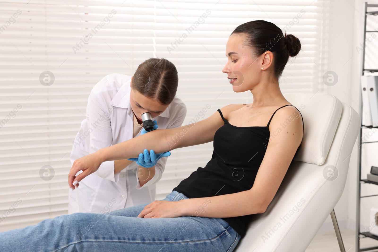 Doctor examining young woman's mole with dermatoscope in hospital Photo of Doctor examining young woman's mole with dermatoscope in hospital