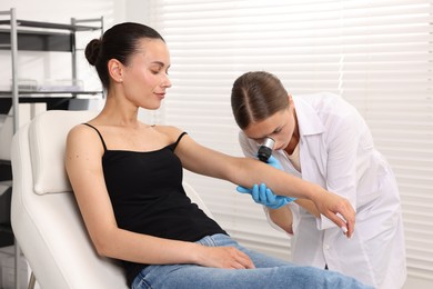 Photo of Doctor examining young woman's mole with dermatoscope in hospital