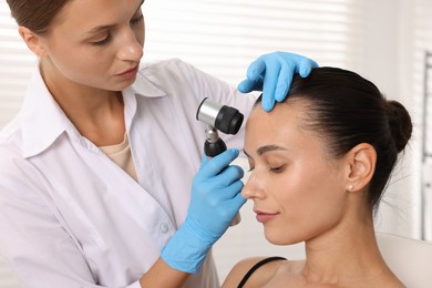 Photo of Doctor examining young woman's mole with dermatoscope in hospital