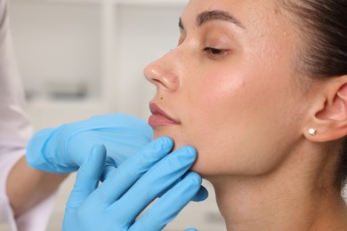 Photo of Doctor examining young woman's mole in hospital, closeup