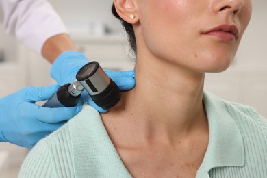 Photo of Doctor examining young woman's mole with dermatoscope in hospital, closeup