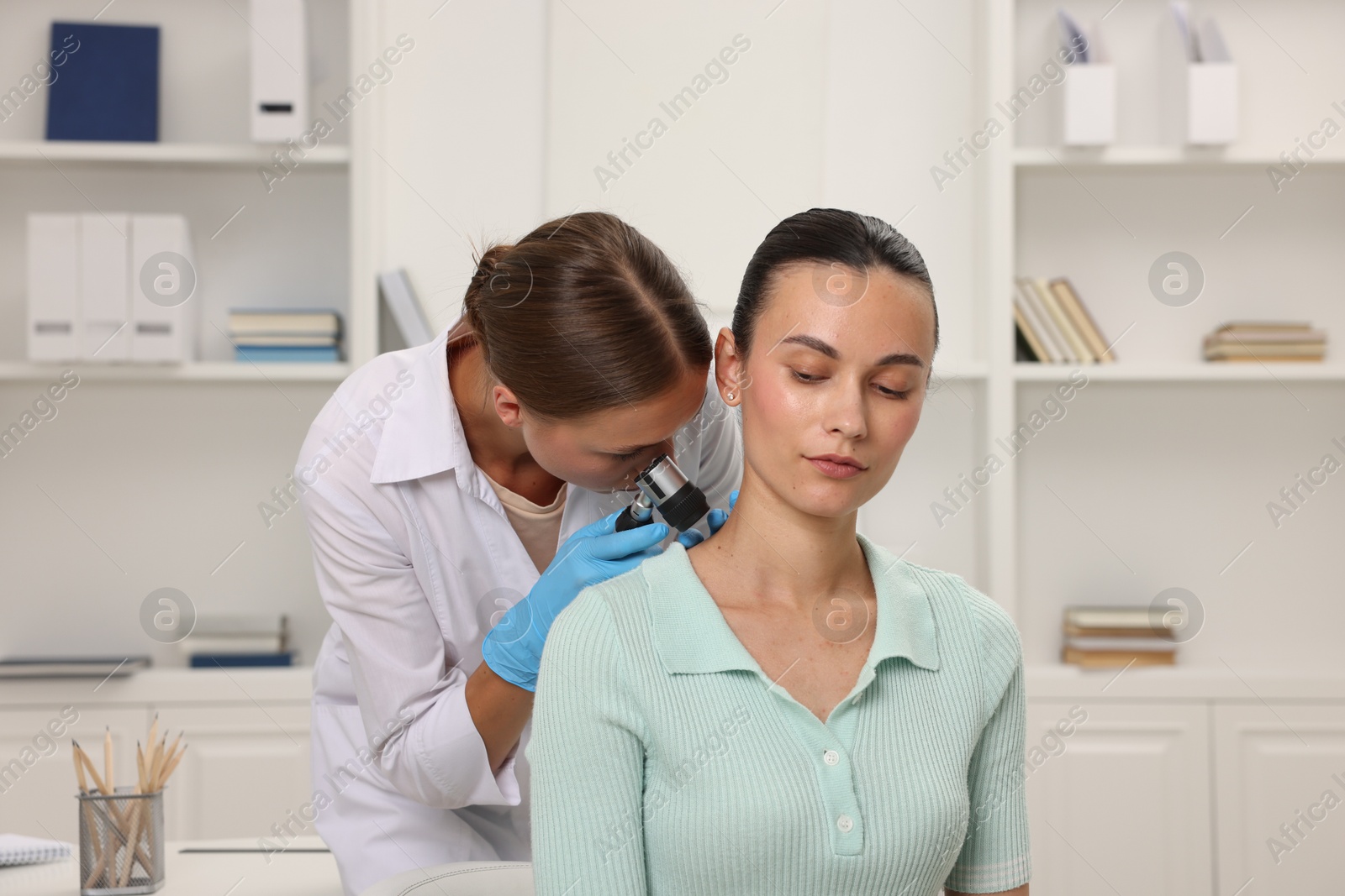 Photo of Doctor examining young woman's mole with dermatoscope in hospital