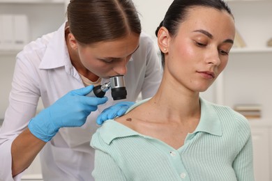Photo of Doctor examining young woman's mole with dermatoscope in hospital