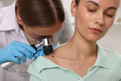 Photo of Doctor examining young woman's mole with dermatoscope in hospital
