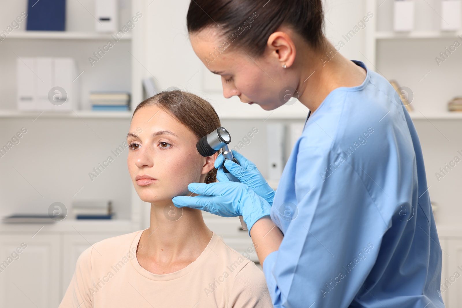 Photo of Doctor examining young woman's mole with dermatoscope in hospital