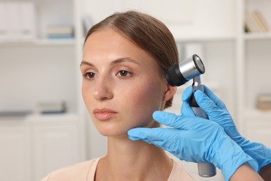Photo of Doctor examining young woman's mole with dermatoscope in hospital