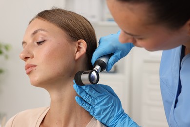 Photo of Doctor examining young woman's mole with dermatoscope in hospital