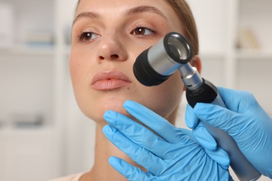Photo of Doctor examining young woman's mole with dermatoscope in hospital, closeup
