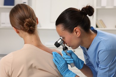 Photo of Doctor examining young woman's mole with dermatoscope in hospital
