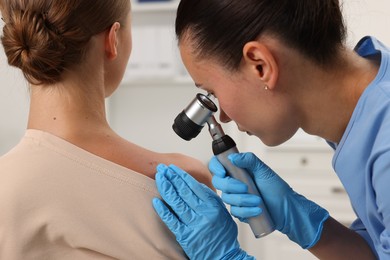 Photo of Doctor examining young woman's mole with dermatoscope in hospital