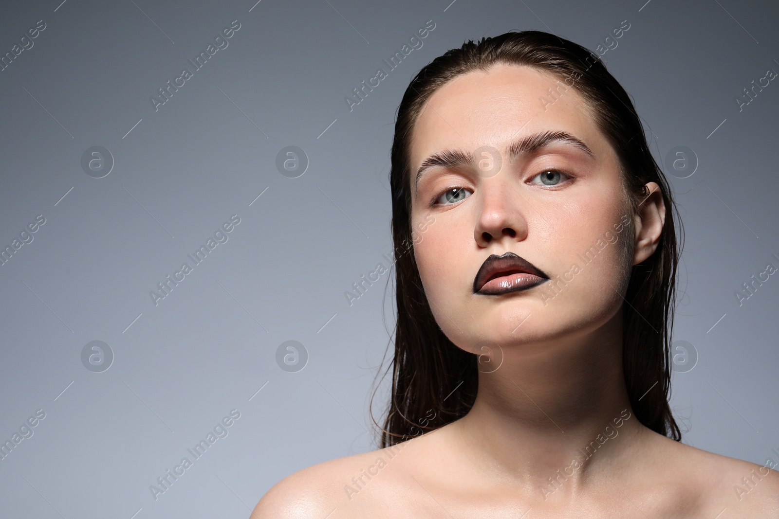Photo of Beautiful young woman with black lip liner on light grey background, space for text