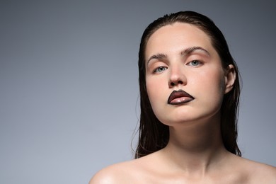 Photo of Beautiful young woman with black lip liner on light grey background, space for text