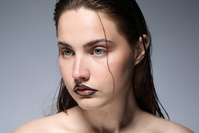 Photo of Beautiful young woman with black lip liner on light grey background