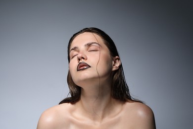 Photo of Beautiful young woman with black lip liner on light grey background