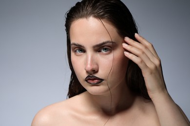 Photo of Beautiful young woman with black lip liner on light grey background