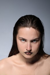 Photo of Beautiful young woman with black lip liner on light grey background