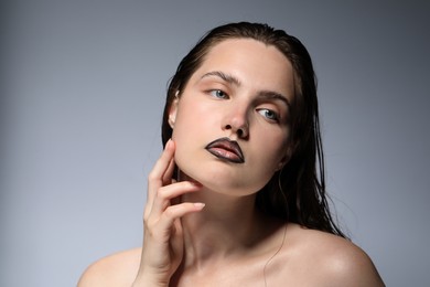 Photo of Beautiful young woman with black lip liner on light grey background