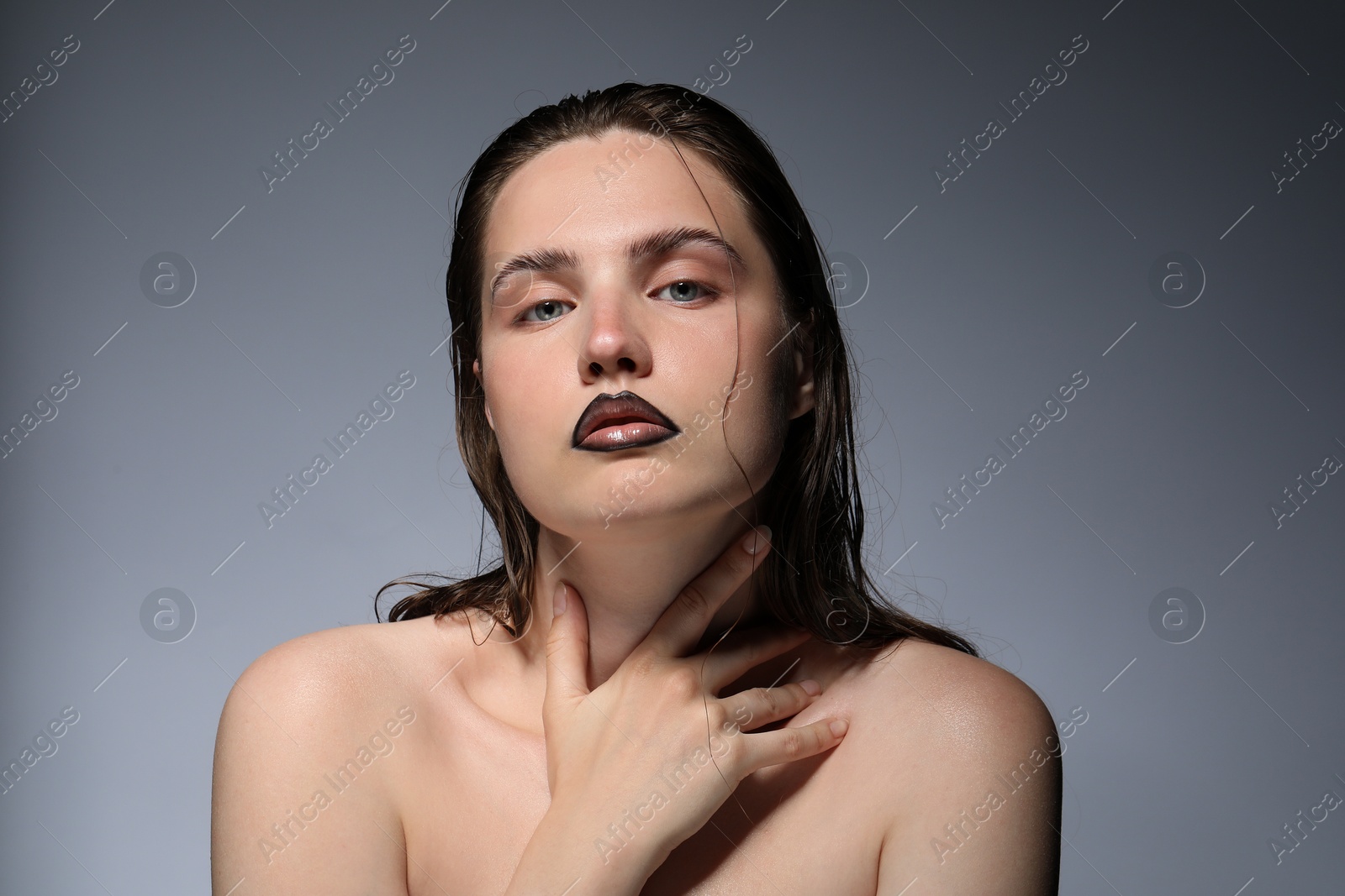 Photo of Beautiful young woman with black lip liner on light grey background