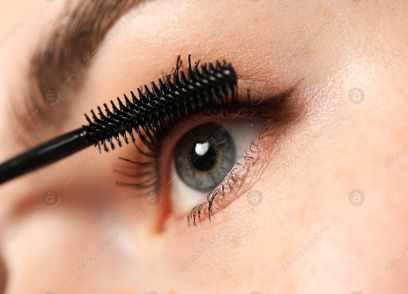 Young woman applying mascara onto her eyelashes, closeup Photo of Young woman applying mascara onto her eyelashes, closeup