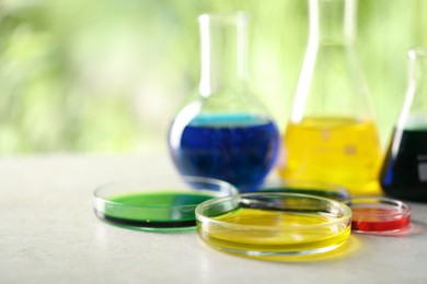 Photo of Laboratory glassware with different samples on light grey table outdoors, closeup. Solution chemistry