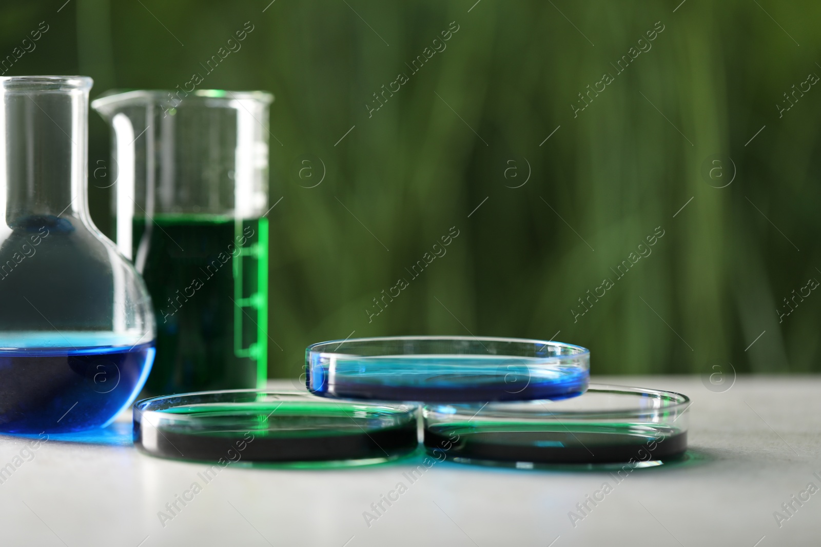 Photo of Laboratory glassware with different samples on light grey table outdoors, closeup. Solution chemistry