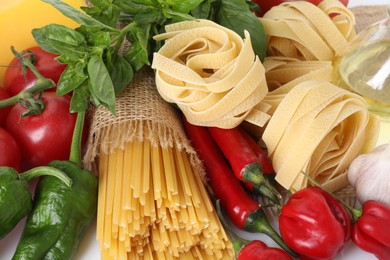 Photo of Different types of pasta and ingredients on table, closeup