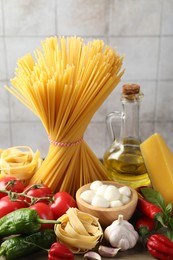 Photo of Different types of pasta and ingredients on table, closeup