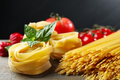 Photo of Different types of pasta and ingredients on wooden table, closeup