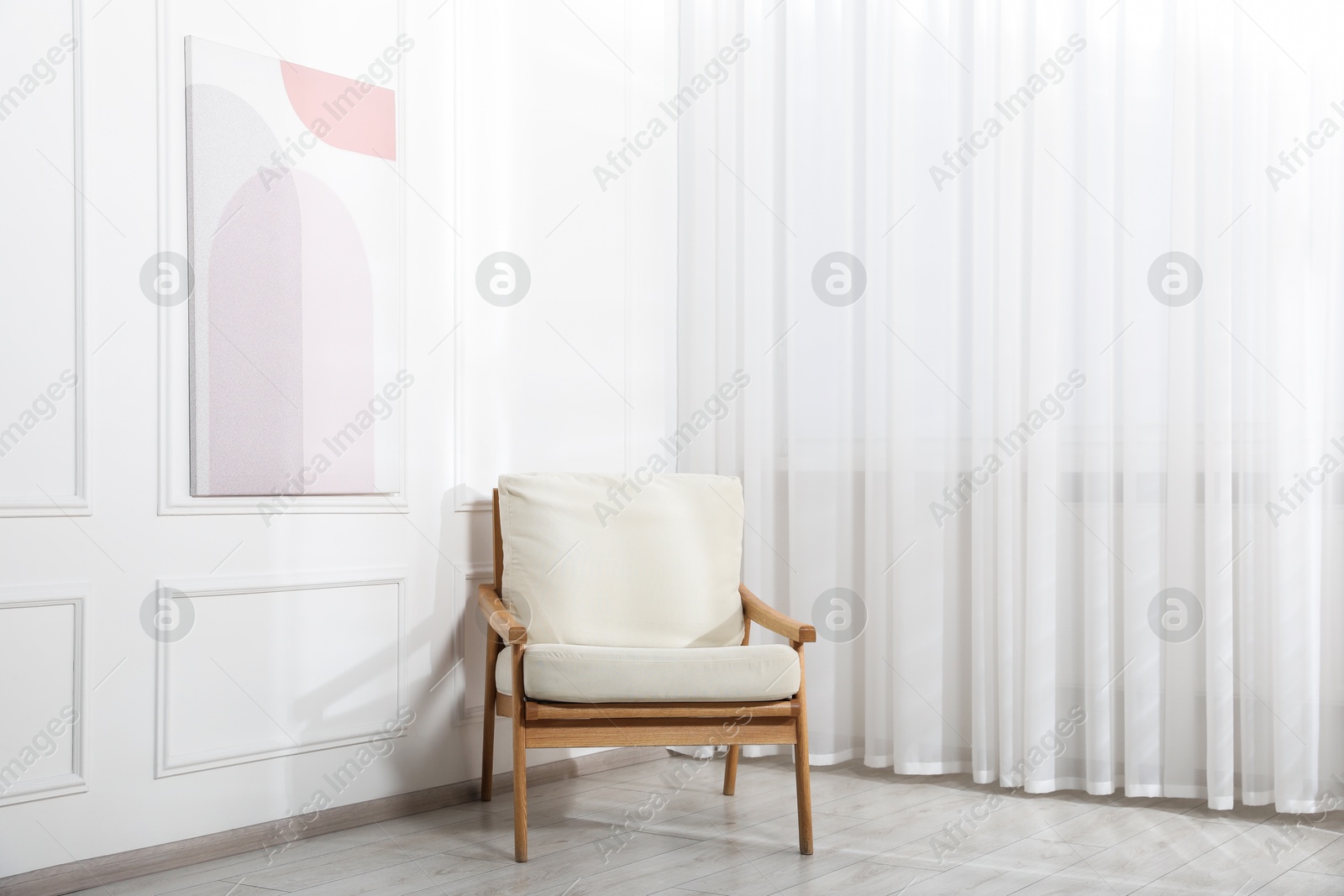 Comfortable beige armchair near window with curtains indoors Photo of Comfortable beige armchair near window with curtains indoors
