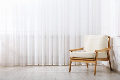 Photo of Comfortable armchair near window indoors, space for text