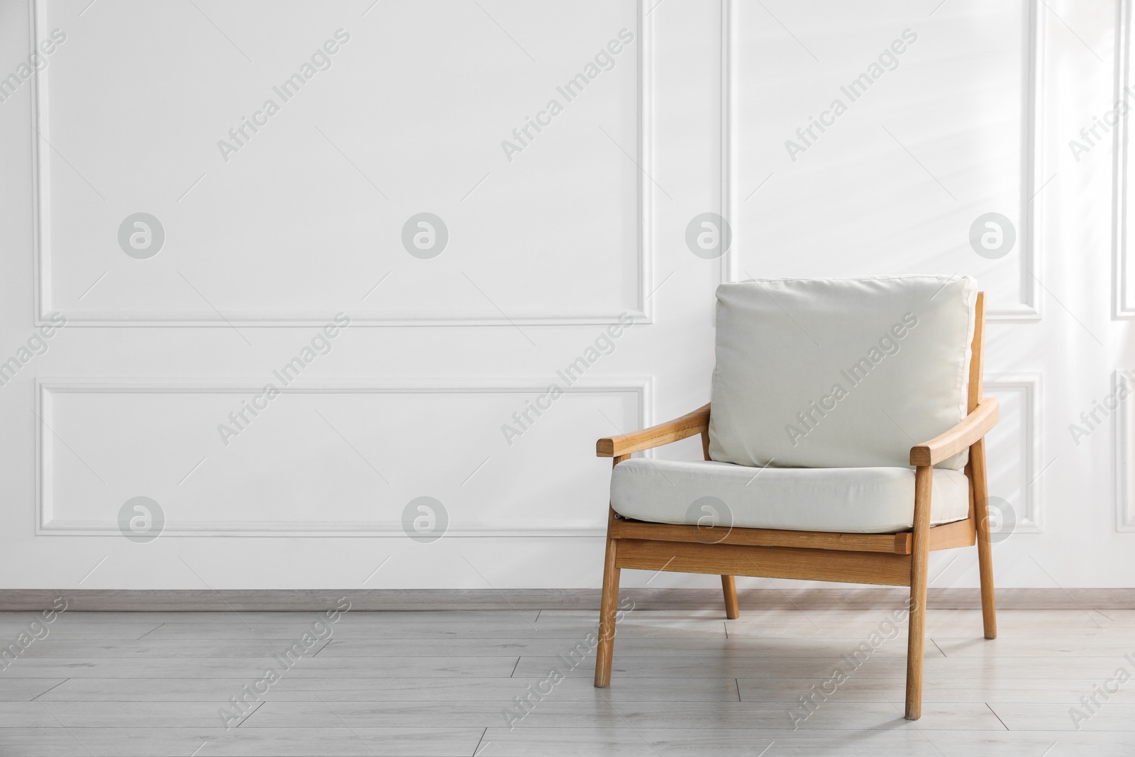 Comfortable armchair near white wall indoors, space for text Photo of Comfortable armchair near white wall indoors, space for text