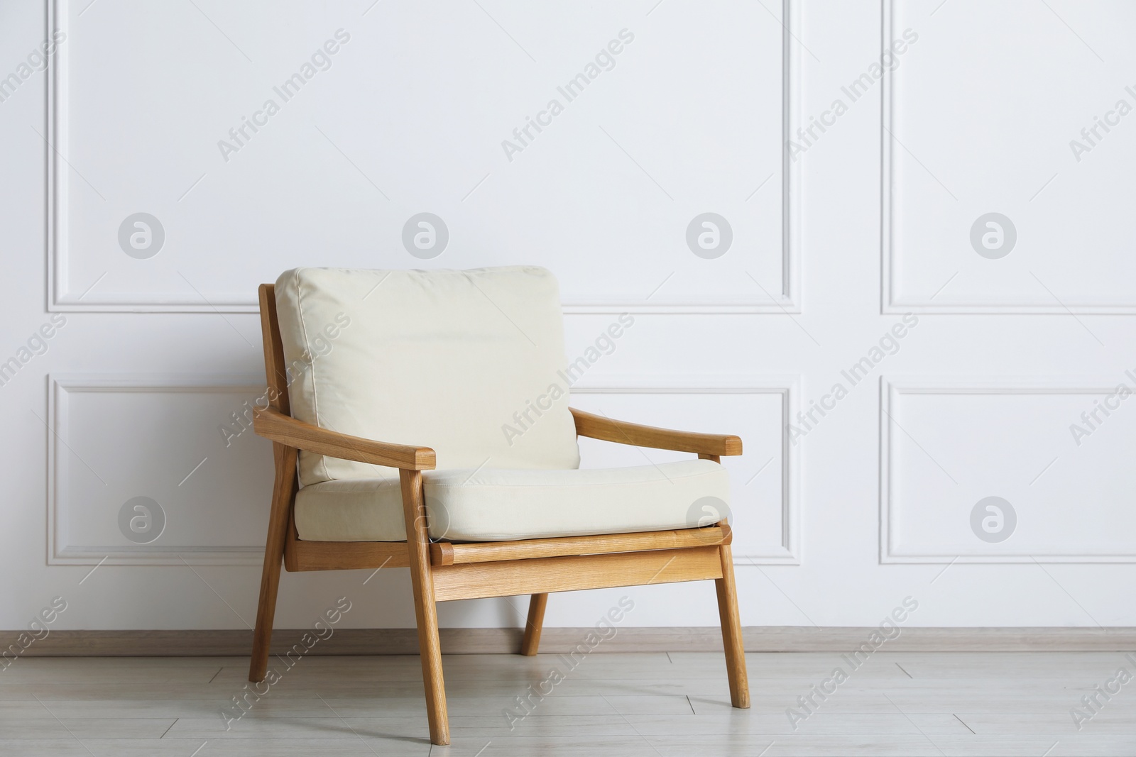 Comfortable beige armchair near white wall indoors Photo of Comfortable beige armchair near white wall indoors