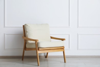 Photo of Comfortable beige armchair near white wall indoors