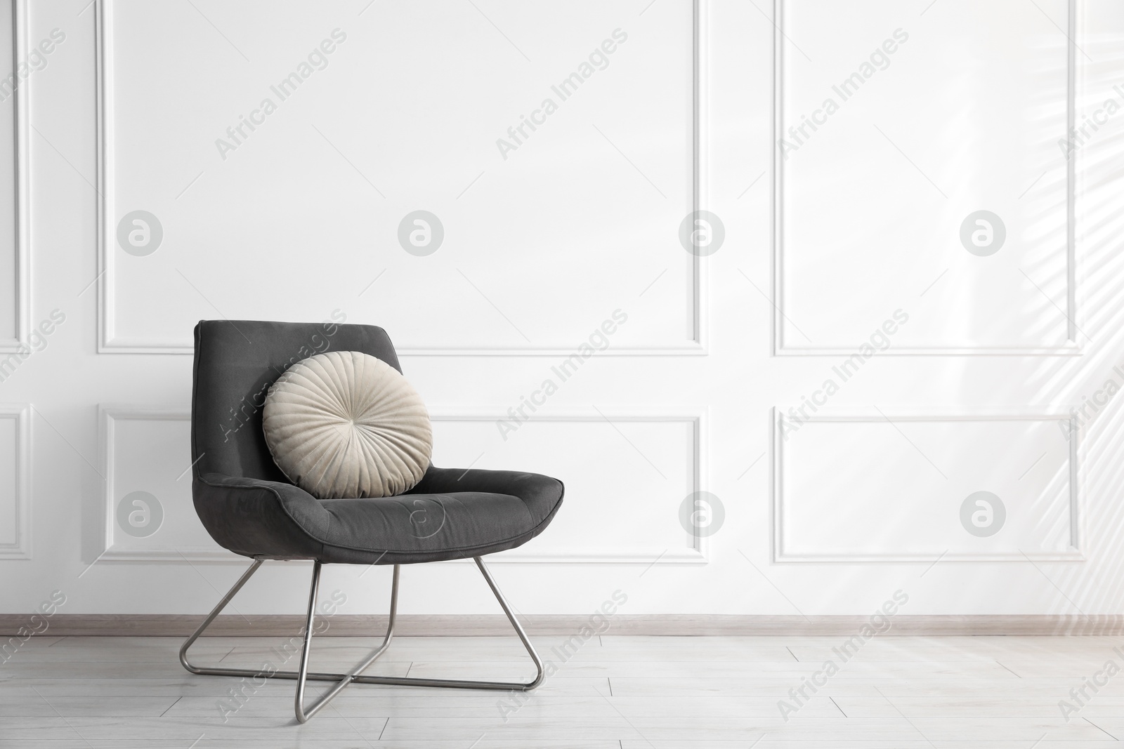 Comfortable armchair with cushions near white wall indoors, space for text Photo of Comfortable armchair with cushions near white wall indoors, space for text