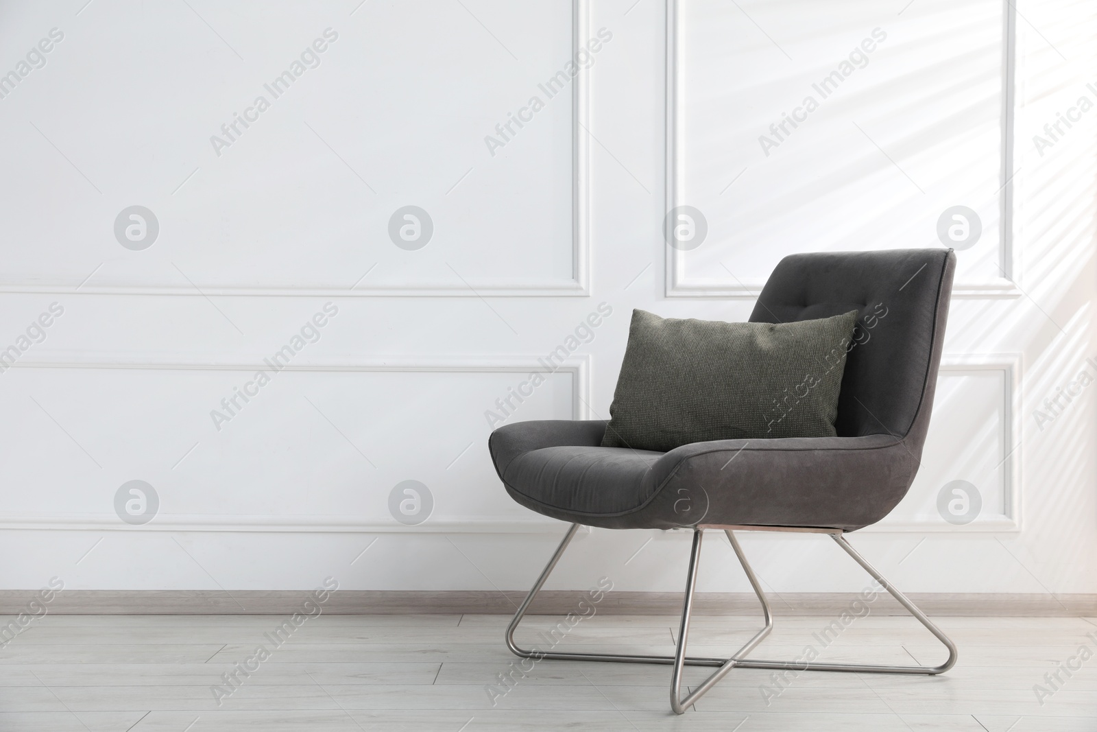 Comfortable armchair with cushion near white wall indoors, space for text Photo of Comfortable armchair with cushion near white wall indoors, space for text