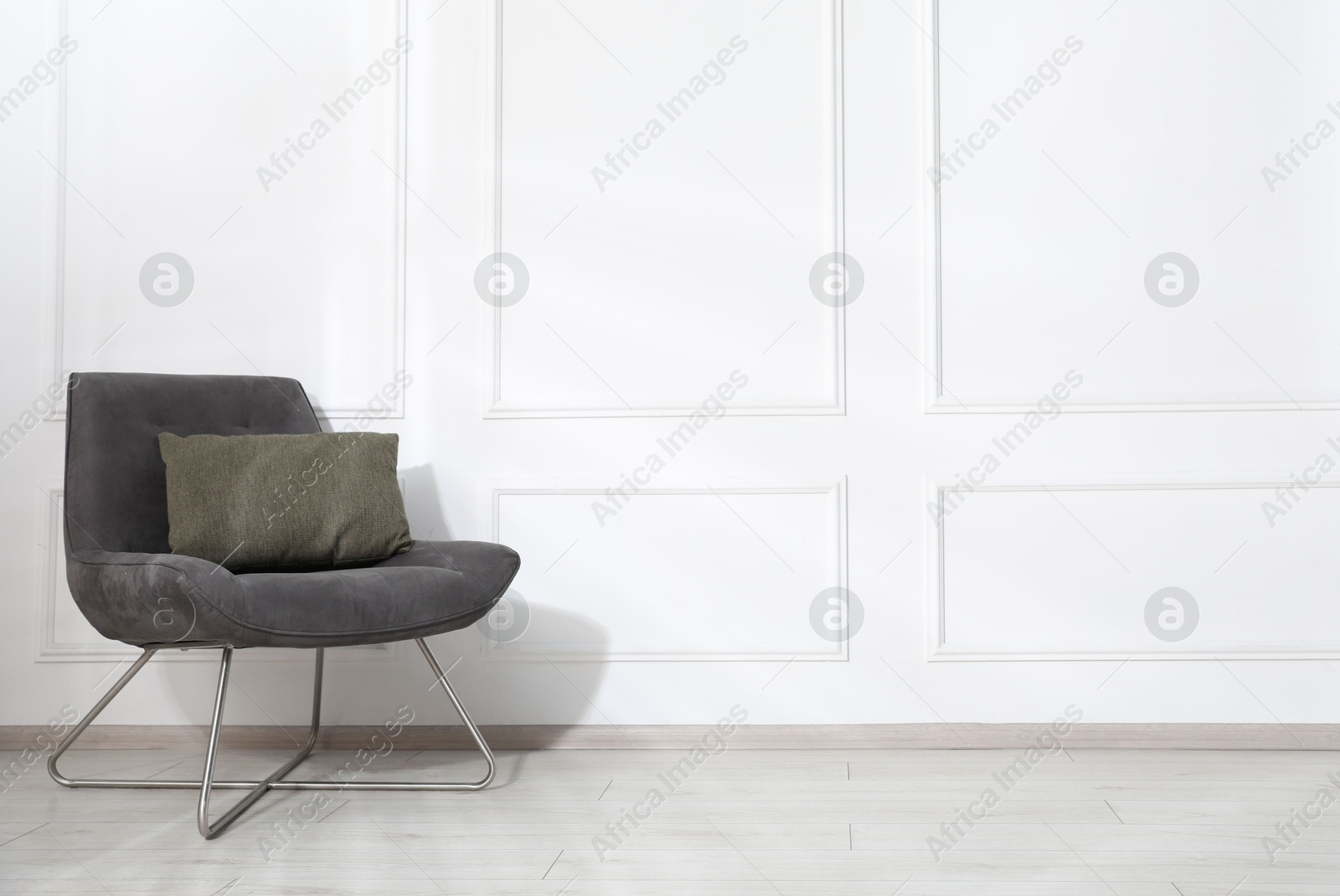 Comfortable armchair with cushion near white wall indoors, space for text Photo of Comfortable armchair with cushion near white wall indoors, space for text